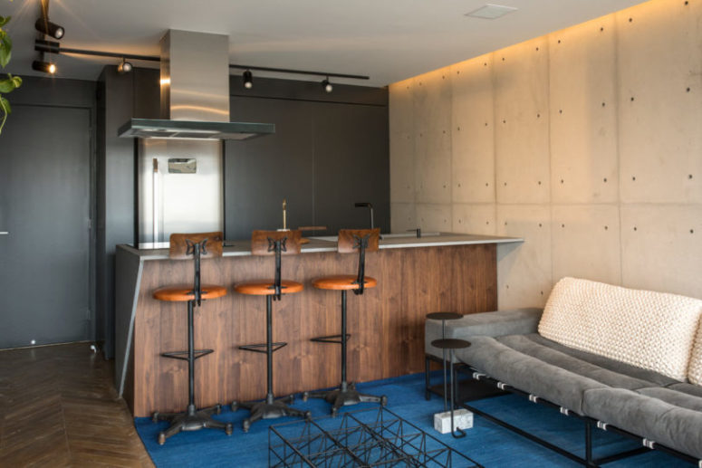 The kitchen is done with sleek black cabinets and a wooden kitchen island with a concrete top
