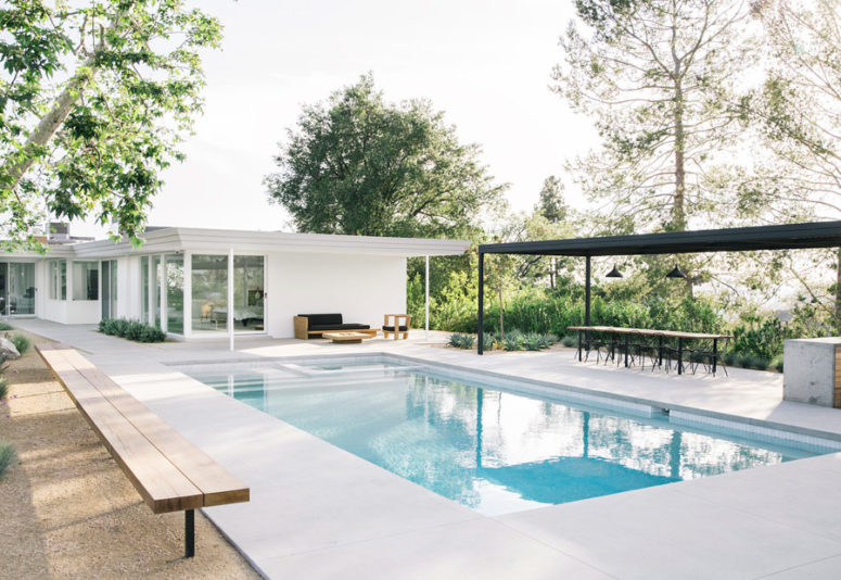 The vast outdoor space features both a sitting and a dining space, a pool and a kitchen island