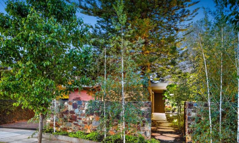 The house is protected with a stone wall and lush greenery to keep it more private