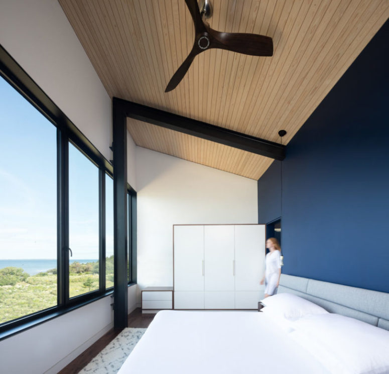 monochrome bedroom design with a statement wall The bedroom is done with a navy statement wall, a glazed wall, an upholstered bed and storage units