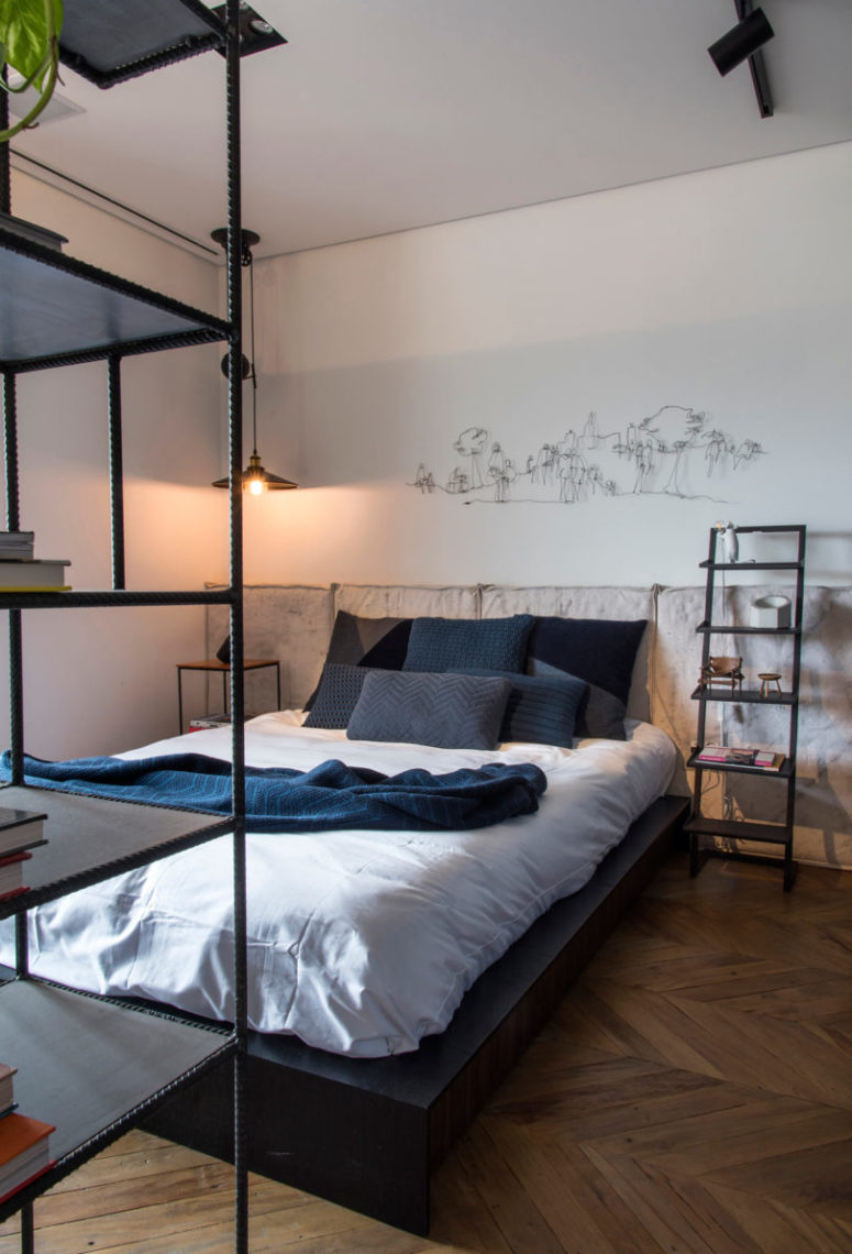 There's a large bed with a comfy upholstered headboard and metal and wood bedside tables