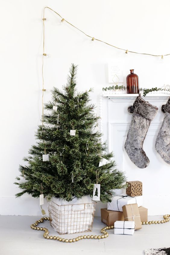 a small and fluffy tree decorated with cardboard ornaments in a wire basket with cotton for a simple Christmas look