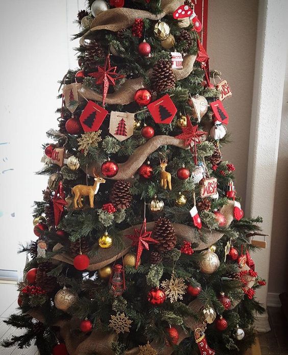 a traditional rustic Christmas tree with silver, gold and red ornaments, pinecones, fake animals, burlap buntings and ribbons