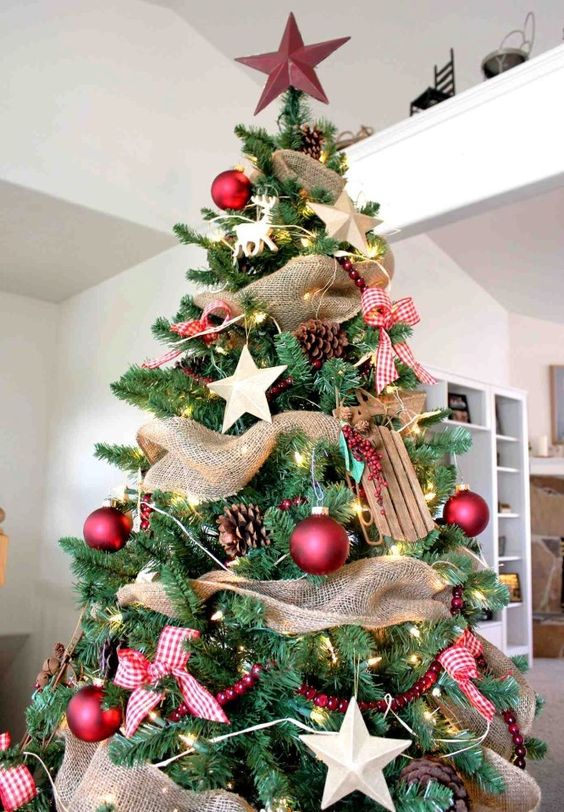 a gorgeous rustic Christmas tree with pinecones, wooden stars and sledges, red balls and plaid bows, a star on top