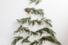 12 a minimalist wall-mounted Christmas tree of evergreens and little copper ornaments on them for an airy feel