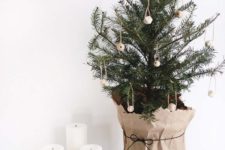 14 a small Christmas tree with wooden ornaments wrapped into kraft paper for a super natural feel