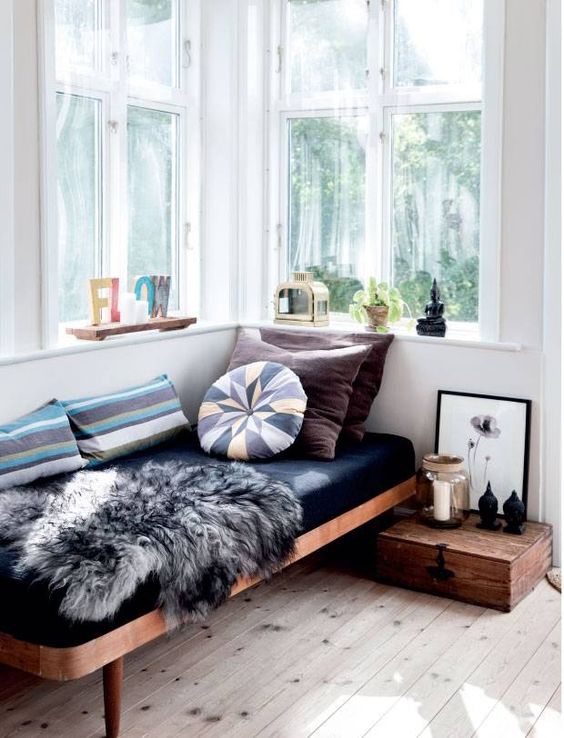 a comfy bench with upholstery, a vintage wooden box for book storage and some candle lanterns for reading during the day