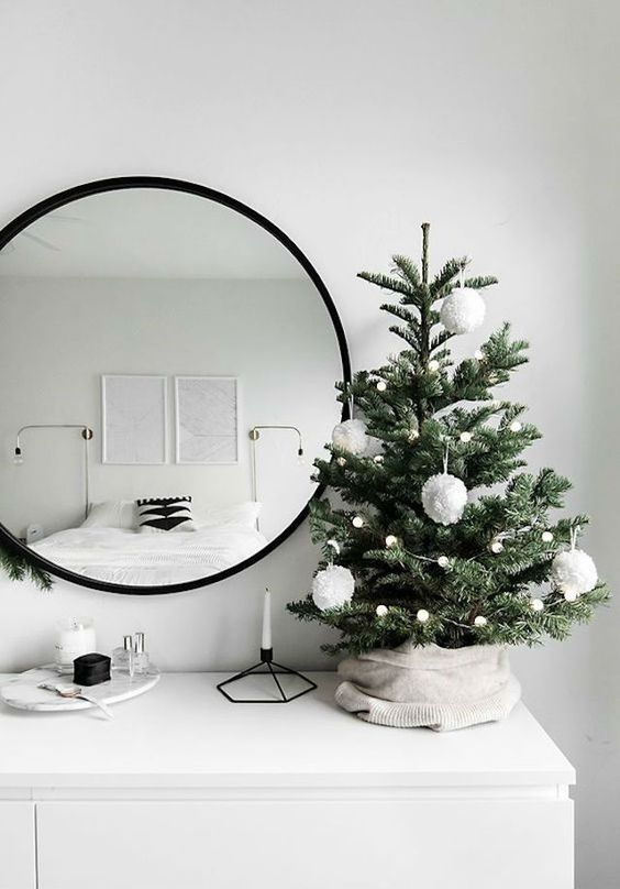 a small tree covered with neutral knit, small and largre pompoms in white for laconic modern decor