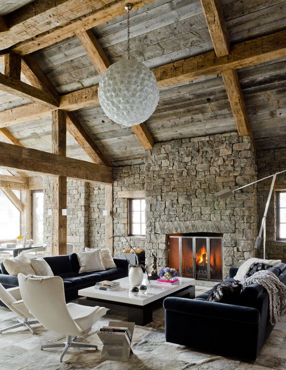 much stone, wooden beams and comfortable modenr furniture upholstered with velvet and a cowhide rug