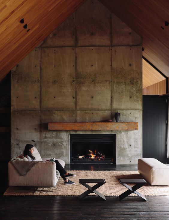 a concrete fireplace wall, a metal mantel and a gable roof clad with wood
