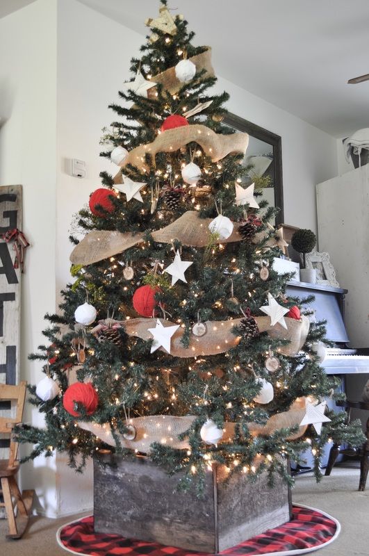 red yarn ball ornaments, white stars and balls, pinecones, burlap ribbons and a weathered wood cover for the base