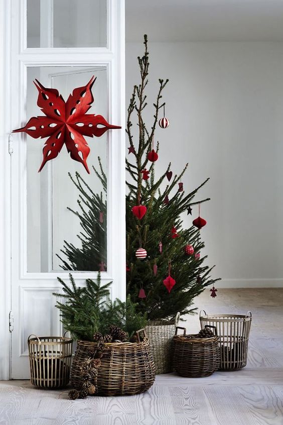 a Scandinavian Christmas tree between modern and traditional with red and white ornaments and baskets around