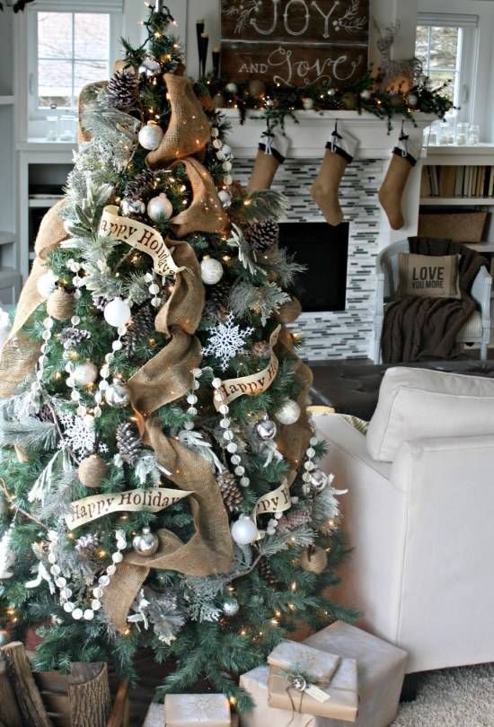 a chic and shiny Christmas tree with burlap ribbons, pompom garlands, snowflakes, white and silver ornaments and pinecones