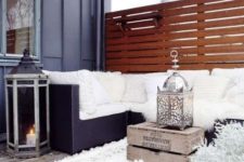 21 a winter terrace with a fur rug, pillows and fluffy throws, a crate with a decorative lantern and candle lantern