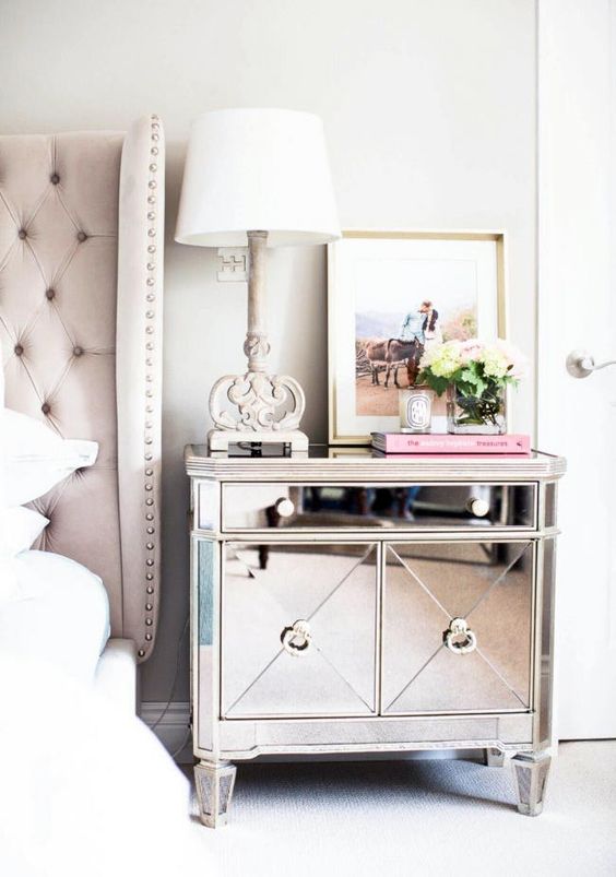 a chic and refined mirror bedside table in a glam space with a blush upholstered bed