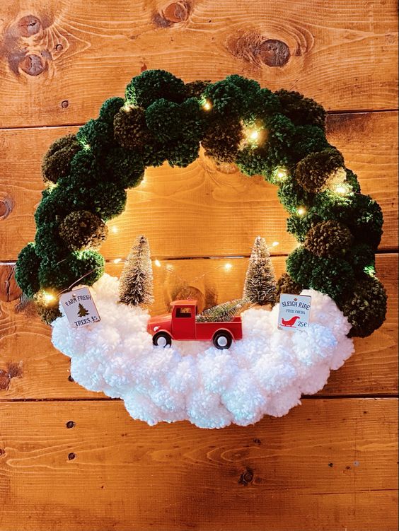 a Christmas pompom wreath in green and white, with bottle brush trees, lights and a lorry is a cool decoration