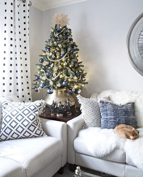 a beautiful vintage-inspired Christmas tree decorated with lights, navy ornaments, beaded garlands, snowflakes and put into a lovely pot