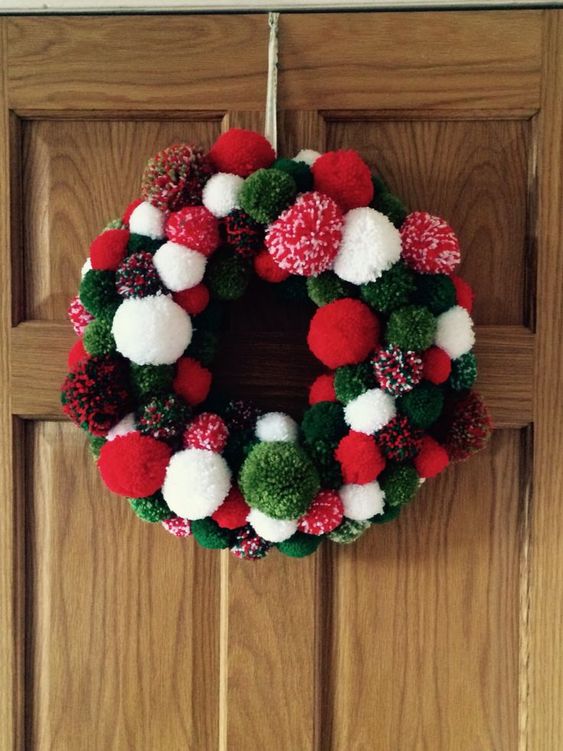 a bright red, green and white pompom Christmas wreath is a cool decor idea for the holidays