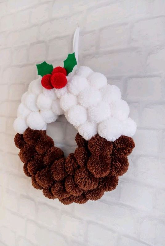 a catchy pompom Christmas wreath in white and brown, with leaves and cranberries is a cool decoration