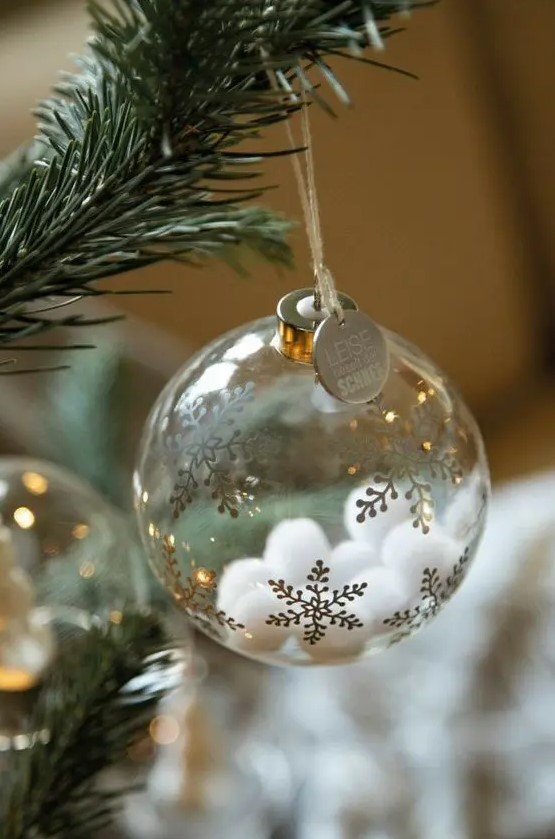 a clear glass Christmas ornament with gold snowflakes and white pompoms inside plus a coin is a cool glam idea to rock