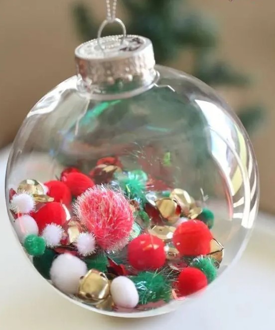 a clear glass Christmas ornament with white, red, green pompoms and gold bells is a cool decor idea done in the traditional colors