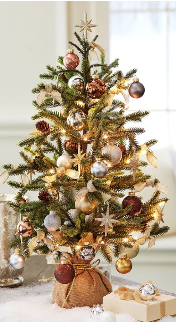 a mini Christmas tree decorated with silver, grey, gold and brown ornaments and lights