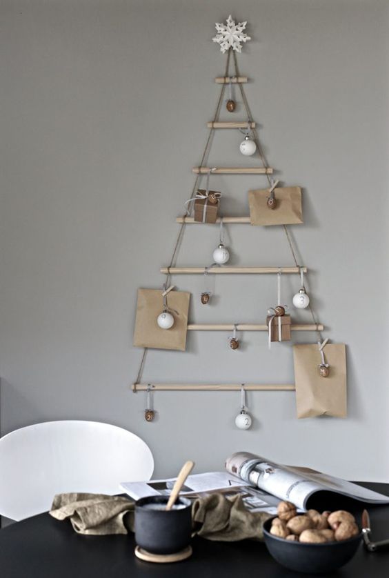 a modern wall-mounted Christmas tree of sticks hanging, with ornaments and gifts, is a cool solution