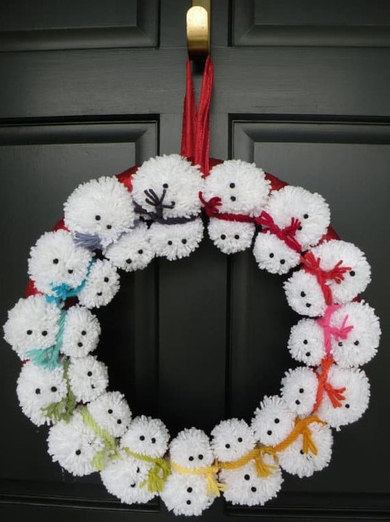 a pompom snowman wreath with colorful rope scarves is a fun front door decor idea for Christmas