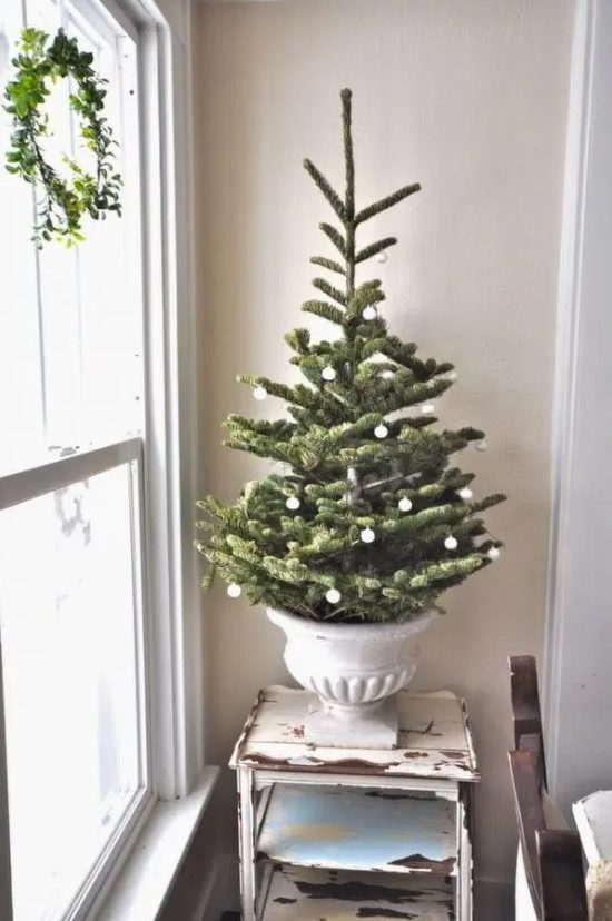 a refined Christmas tree in an urn, with small white ornaments is a very elegant and cool idea