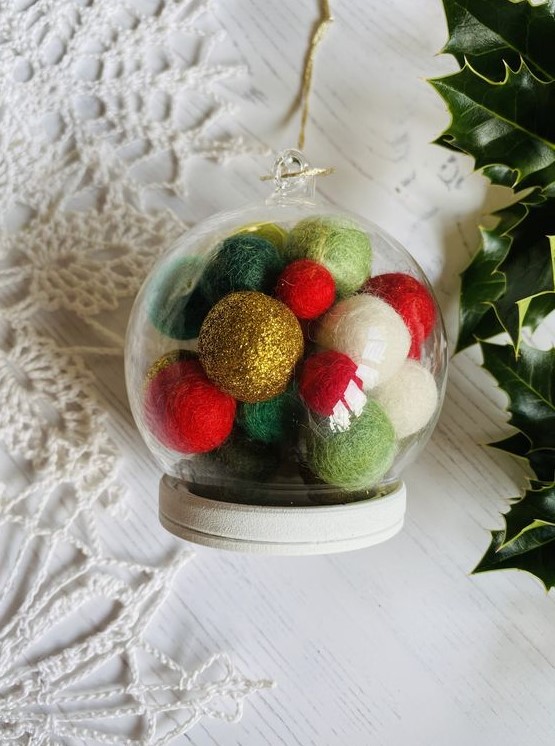 a sheer glass ornament with colorful pompoms inside is a very creative and bright decoration for winter holidays