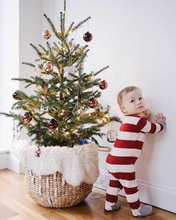 a small Christmas tree in a basket with faux fur, with chocolate brown and gold ornaments is a modern and stylish solution