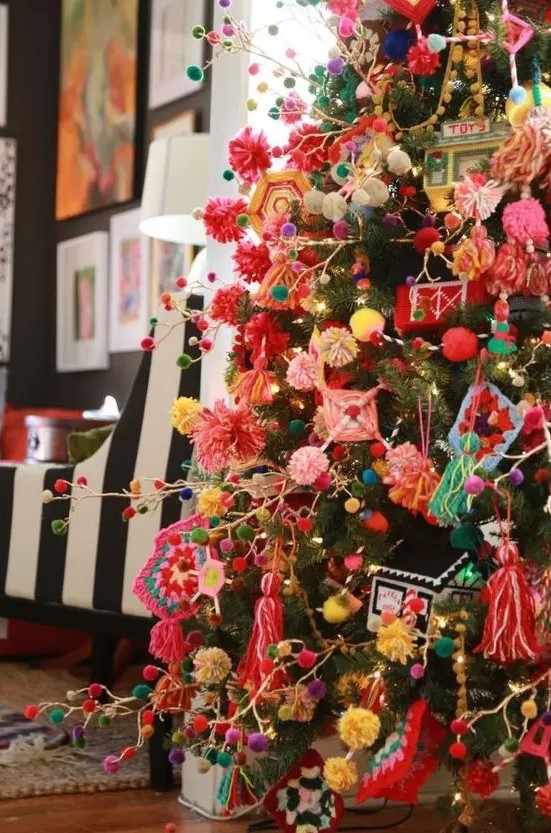 a super colorful Christmas tree decorated with bright pompom garlands and ornaments, with tassels, macrame and various yarn decor looks fun