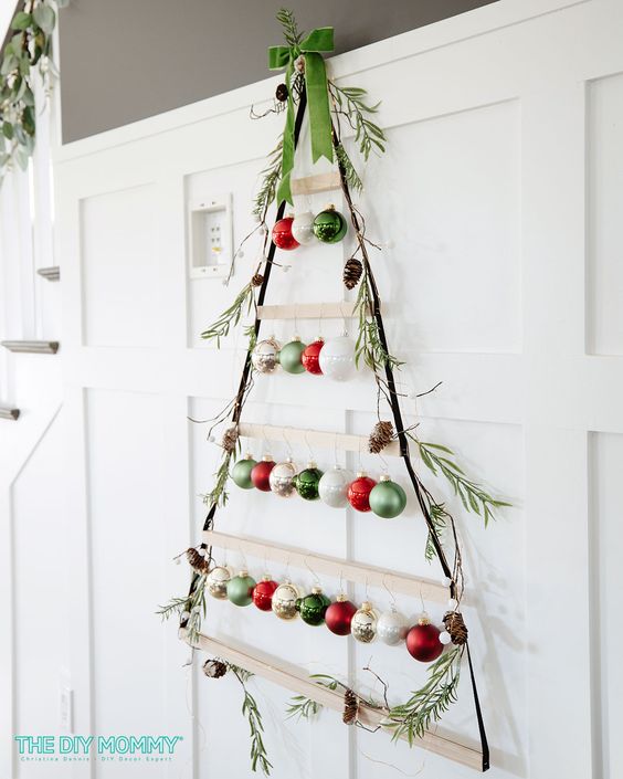 a wall-mounted Christmas tree of ledges, rope and colorful ornaments with greenery is lovely