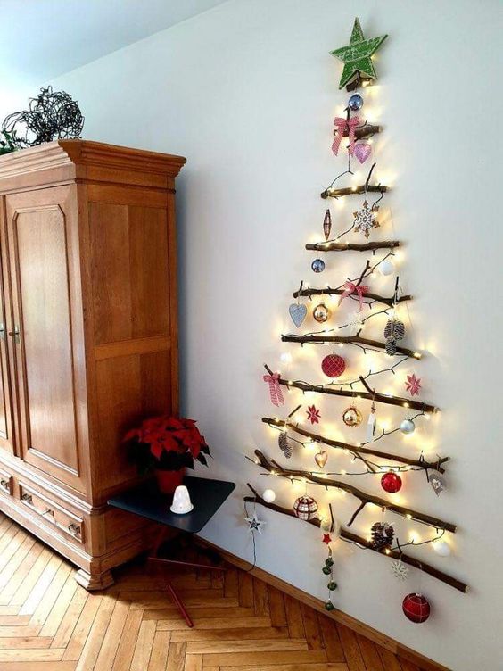 a wall-mounted Christmas tree of lights and branches, with ornaments and a star topper is cool