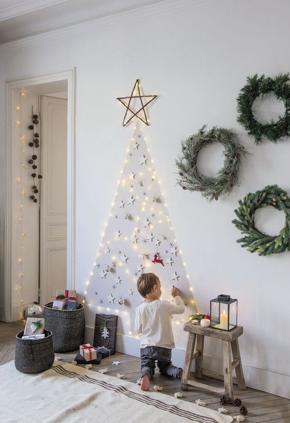 a wall-mounted lights Christmas tree with paper stars is a cool alternative to a usual Christmas tree