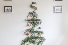 a wall-mounted pine branch Christmas tree with gold and grey ornaments is a bold and catchy idea