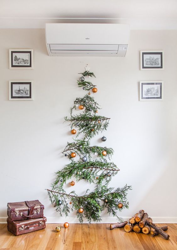 a wall-mounted pine branch Christmas tree with gold and grey ornaments is a bold and catchy idea
