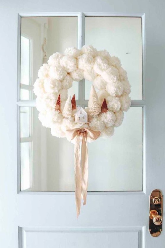 a white pompom Christmas wreath with tinsel trees and a small house plus a silk ribbon bow is very exquisite and cozy