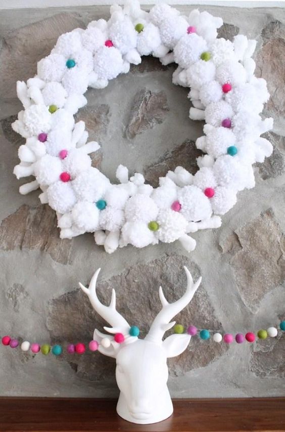 a white pompom and snowflake wreath with colorful mini pompoms is a cool Christmas decoration