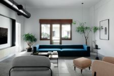 02 The living room is done with a stylized metal pipe, neutral coomfy furniture and a bold blue sofa