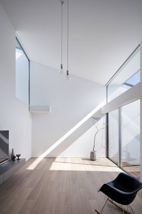 a minimalist space with an attic roof, much natural light coing through glazings and a minimum of furniture