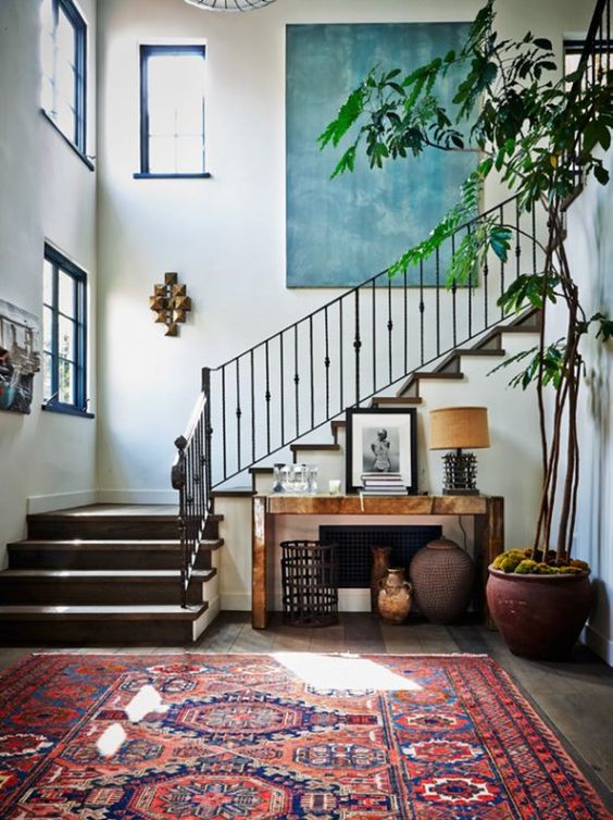an eclectic entryway done with a boho chic rug and a modern console table, with a statement artwork