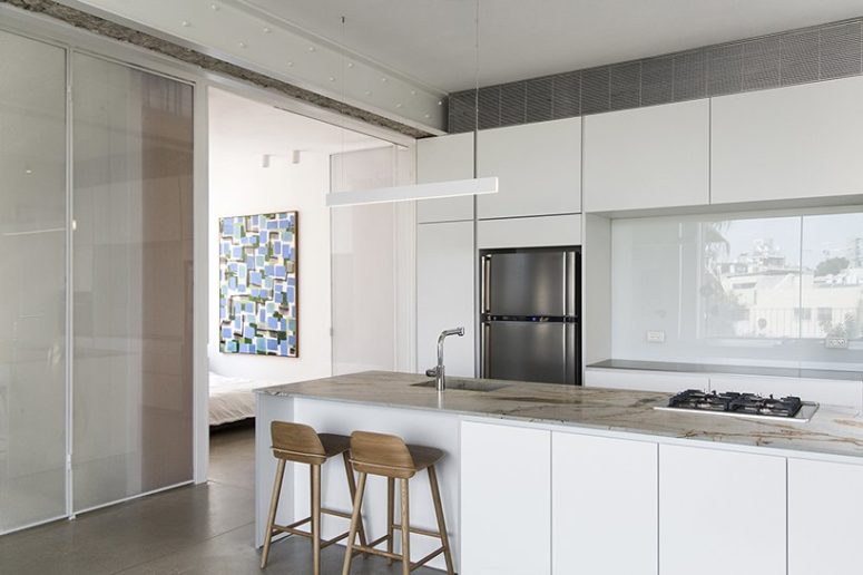 kitchen island with practical eating space The kitchen is done with white sleek cabinets and some wooden stools, the kitchen island features a meal space