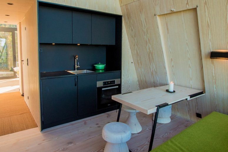 The main space is a dining living kitchen one, with black cabinets, a comfy table and stools and a bright upholstered bench The main space is a dining-living-kitchen one, with black cabinets, a comfy table and stools and a bright upholstered bench