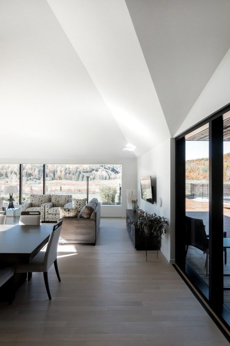 minimalist open layout design The main space of the house is an open layout with a living room, kitchen and dining space done in minimalist style
