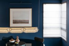 05 The dining space is done with navy upholstered chairs and a large glass round dining table