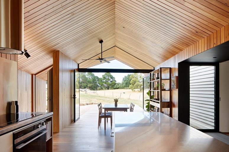 The kitchen is united with a dining space, the whole space is opened up to outdoors with glass doors
