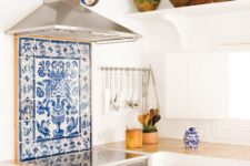 05 a blue mosaic tile backsplash, matching ceramics and plates on the wall and white cabinets for a Mediterranean space