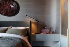 06 The bedroom features a beautiful rounded wall, an upholstered bed, artworks and floating bedside tables