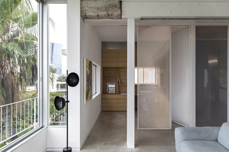 tiy home office hidden behind storage system The home office is hidden behind a semi sheer panel, there's a large shelving unit and a comfy desk